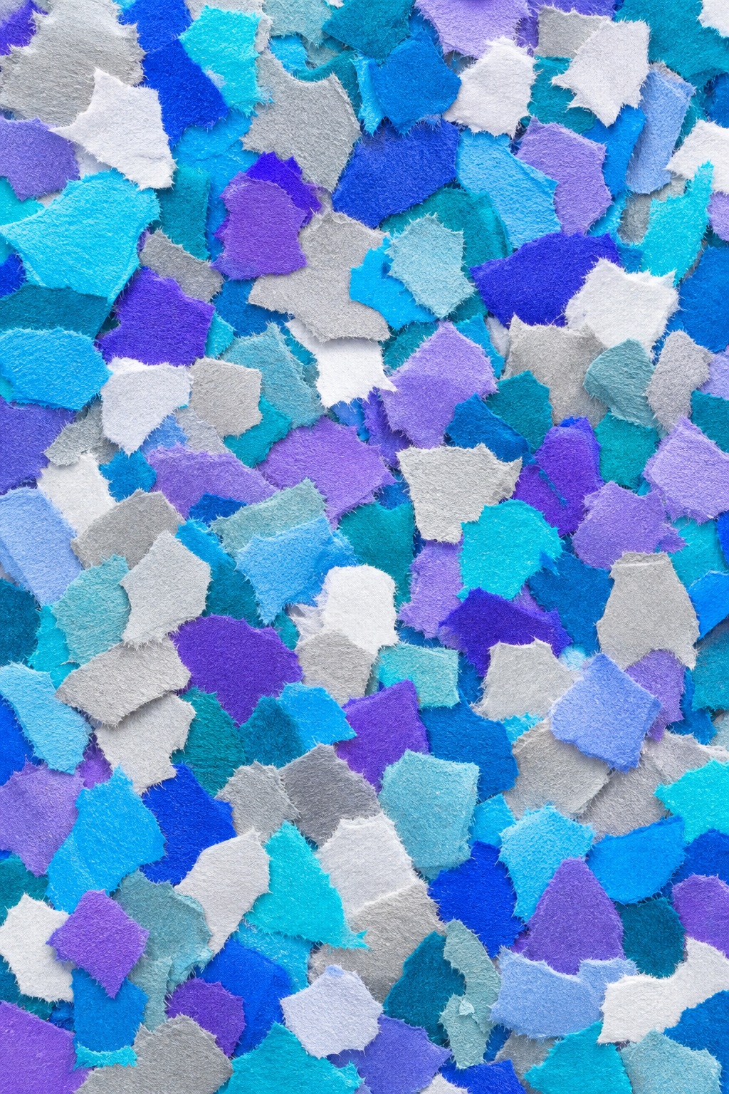 Blue, purple, white, and teal paper confetti pieces scattered across a textured background.
