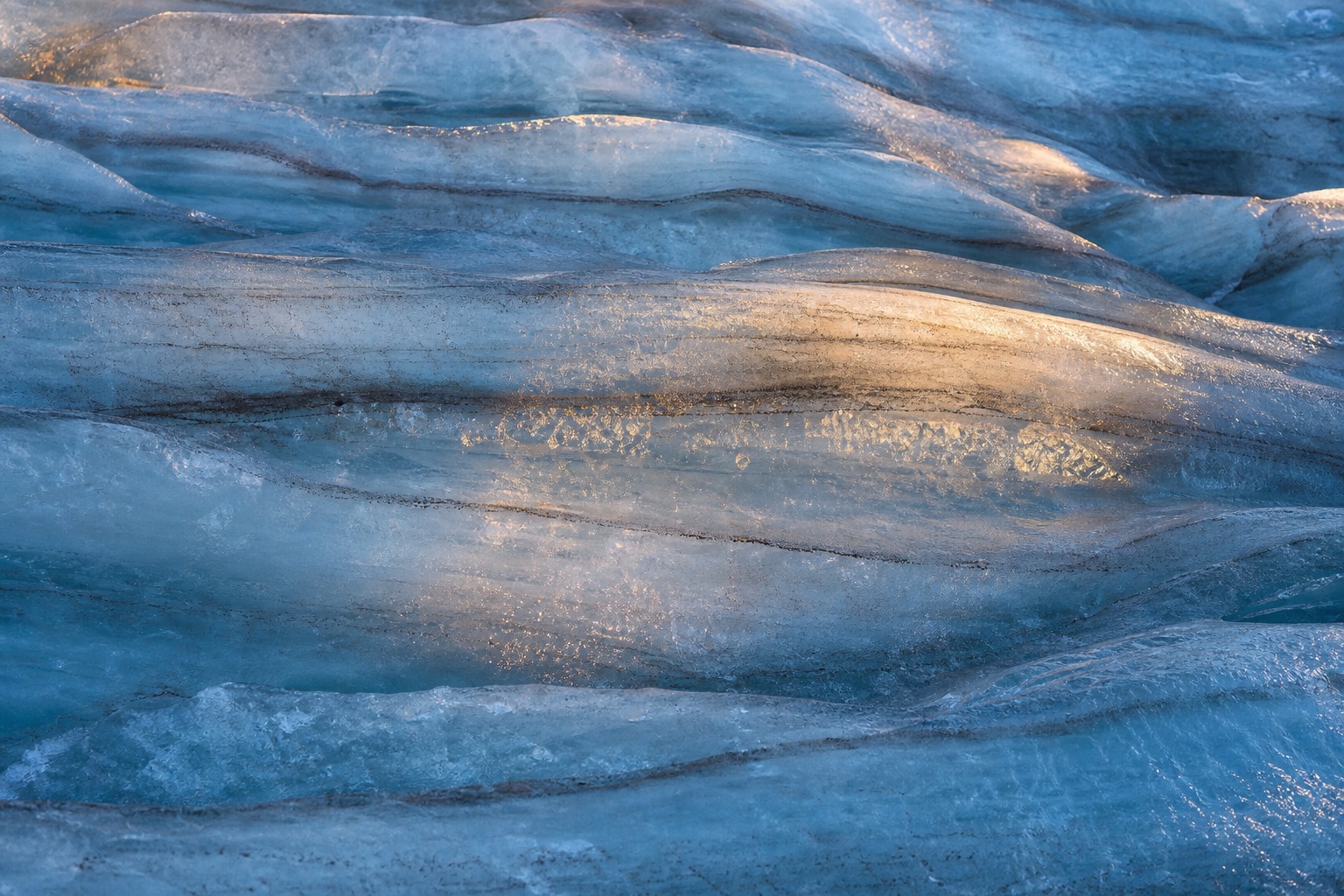 Blue glacier ice with crevasse texture and warm reflected light bands