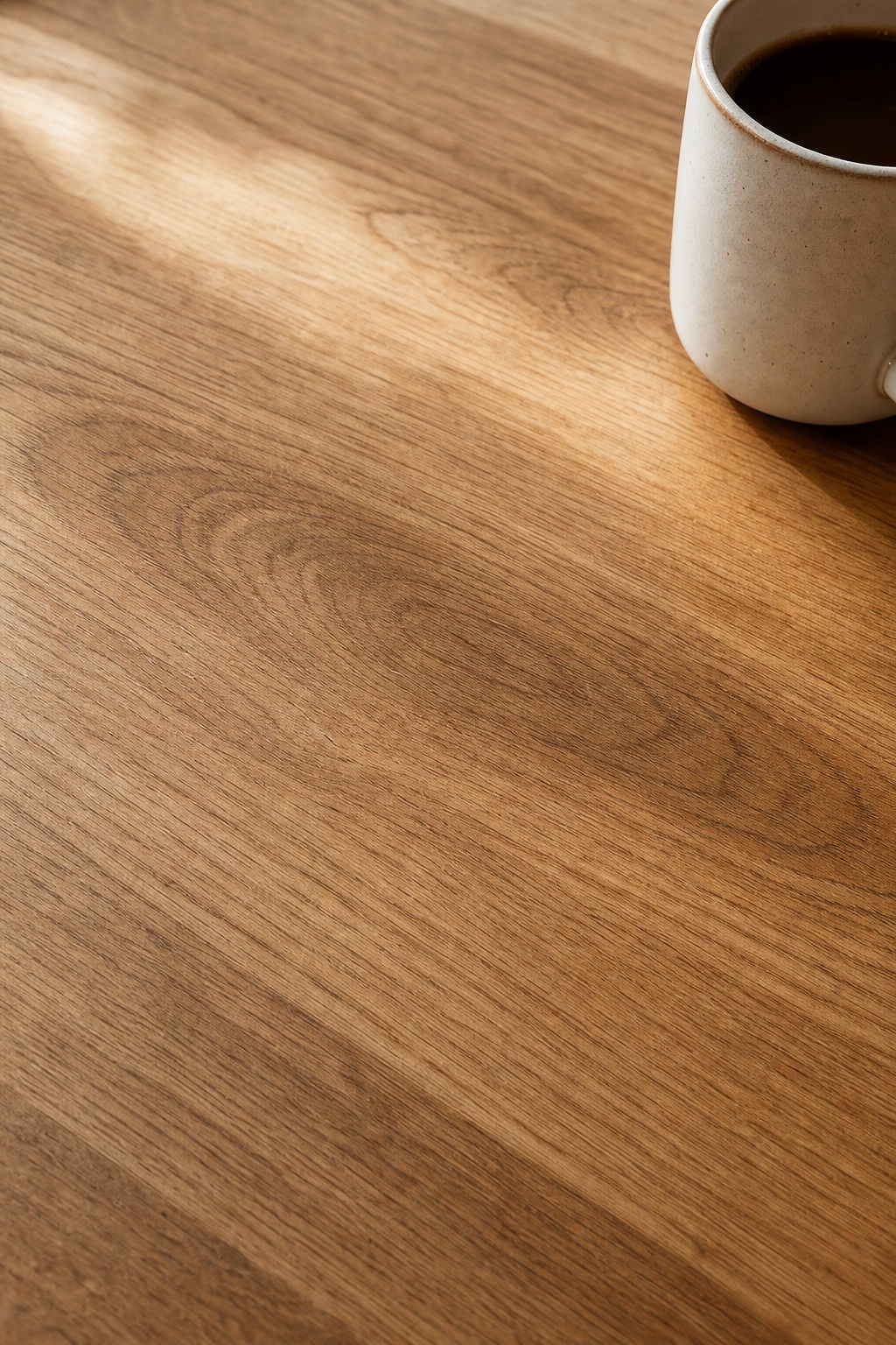 Vertical woodgrain desk surface with a mug in the upper right corner