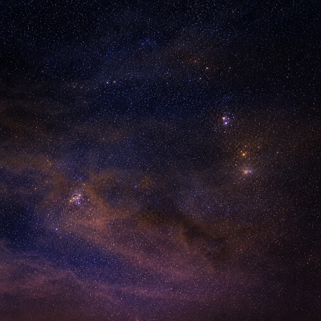 Gold and indigo night sky with scattered stars and a faint distant light cluster