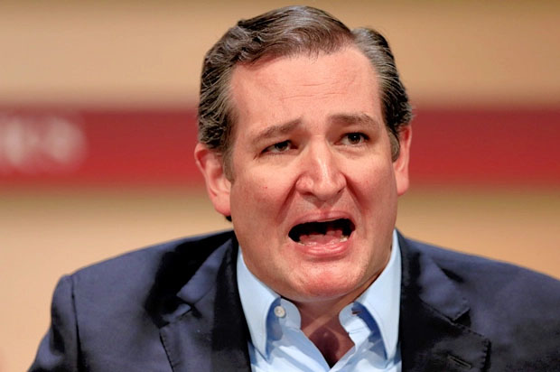 Close-up of a man in a suit speaking with a blurred indoor background.