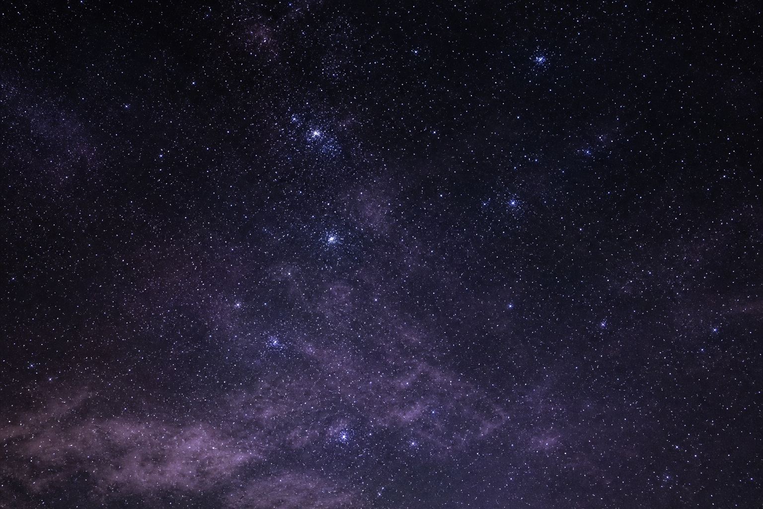 Violet black star field with a faint distant light cluster in the night sky