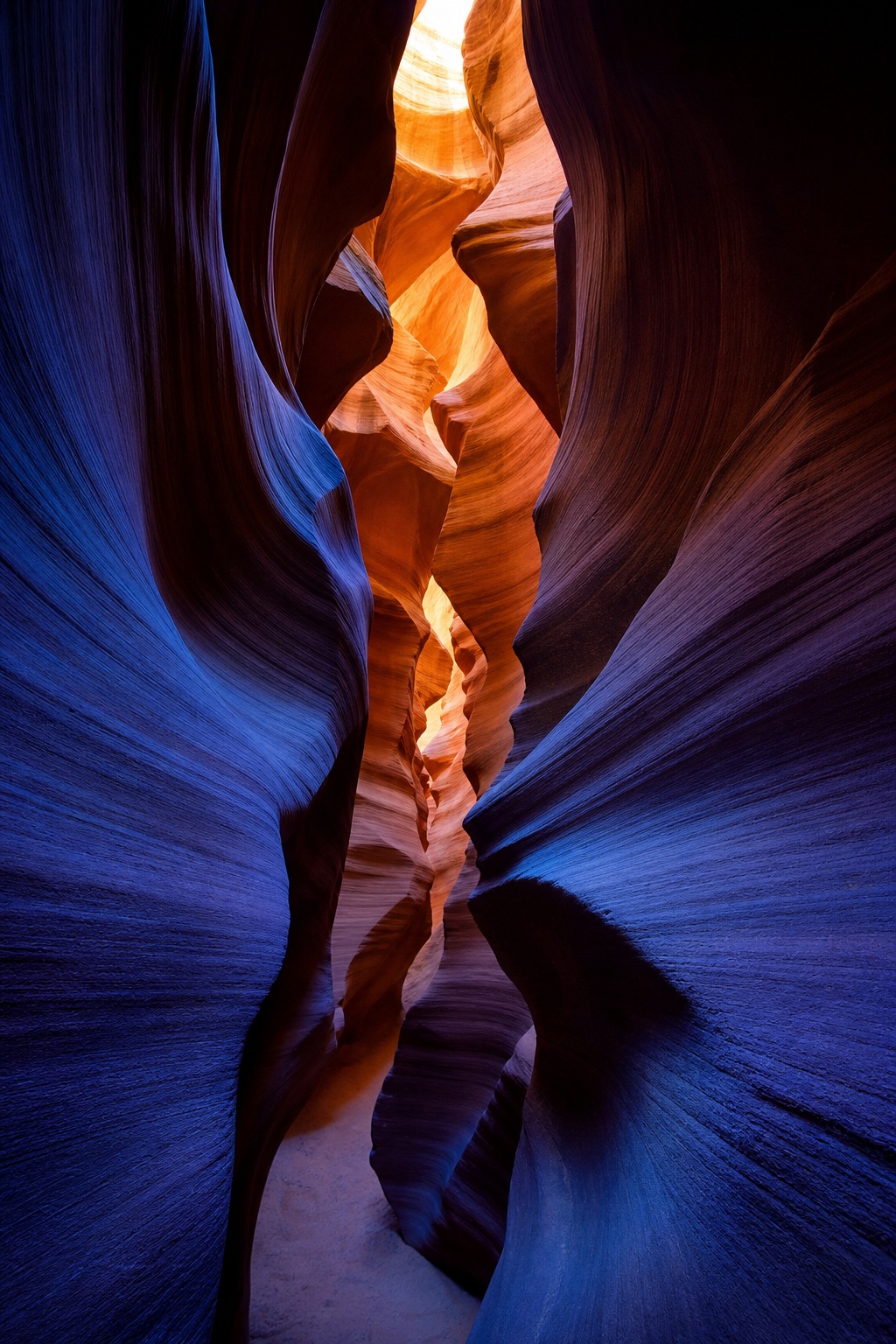 Narrow slot canyon with curved sandstone walls and deep blue shadows