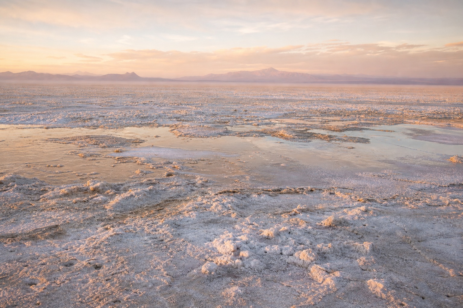 Wide salt flat landscape with warm late-day light and distant basin horizon.