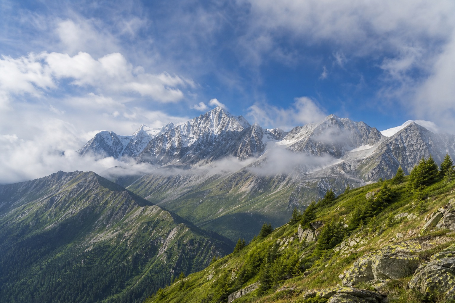 Misty mountain range with clouds drifting over green slopes and rocky peaks