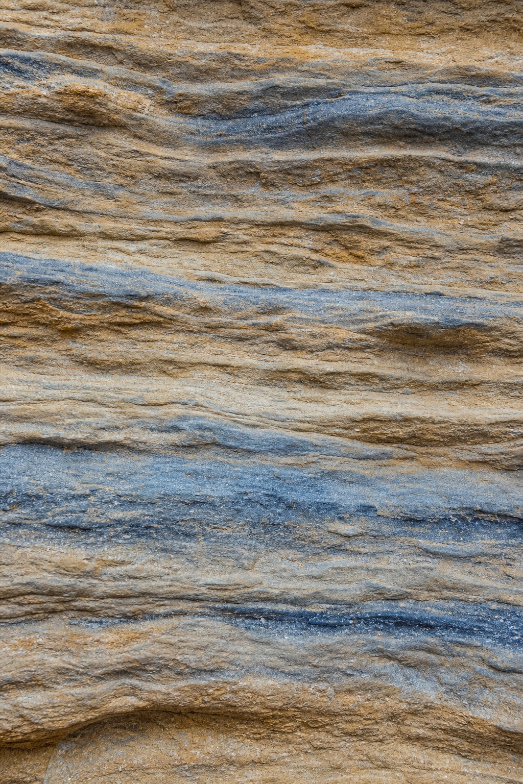 Blue and tan layered sandstone texture with weathered horizontal striations.