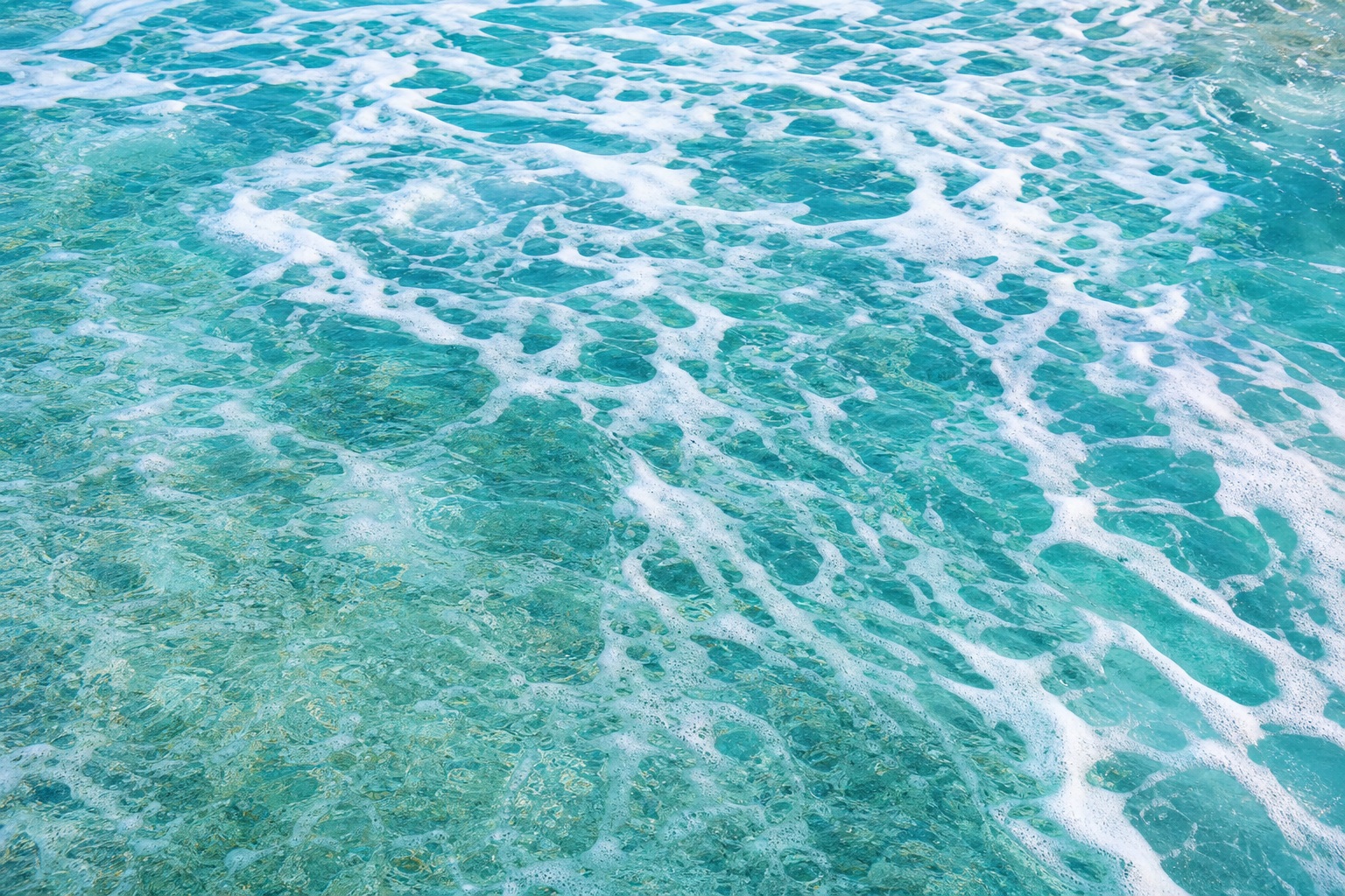 Blue ocean water with white sea foam and tidal patterns