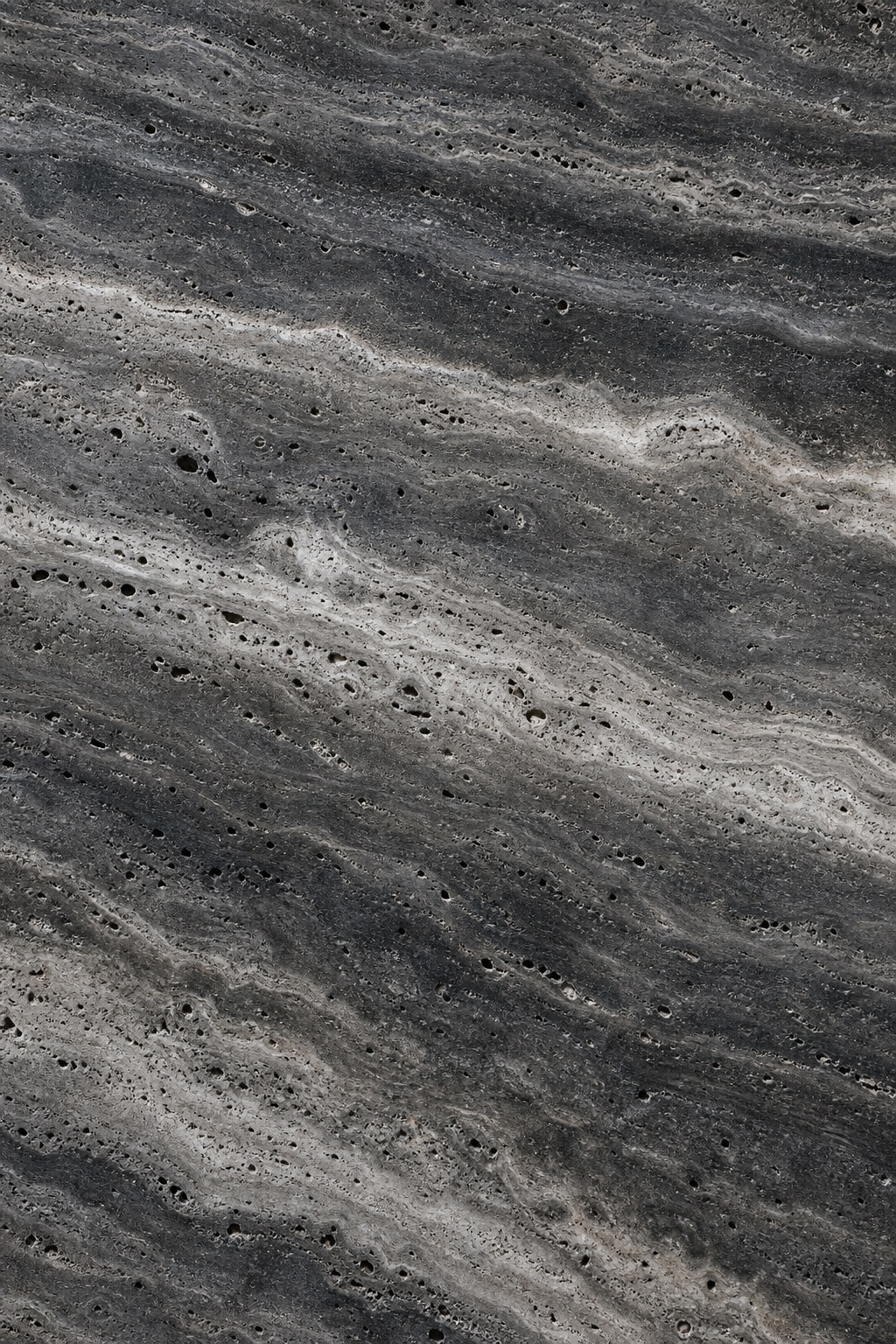 Dark smoky charcoal travertine stone surface with layered natural pores and bands