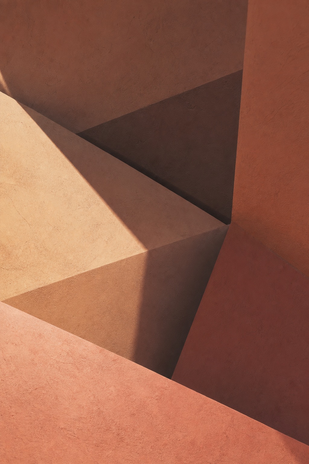 Warm-toned abstract folded planes with sharp geometric shadows and soft light gradients.