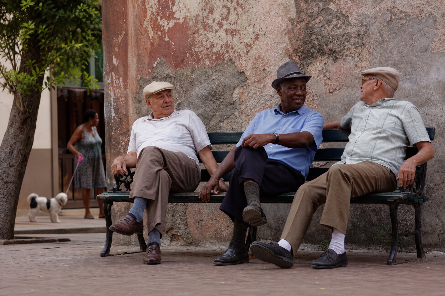 Three elderly men sitting on a bench along a city sidewalk