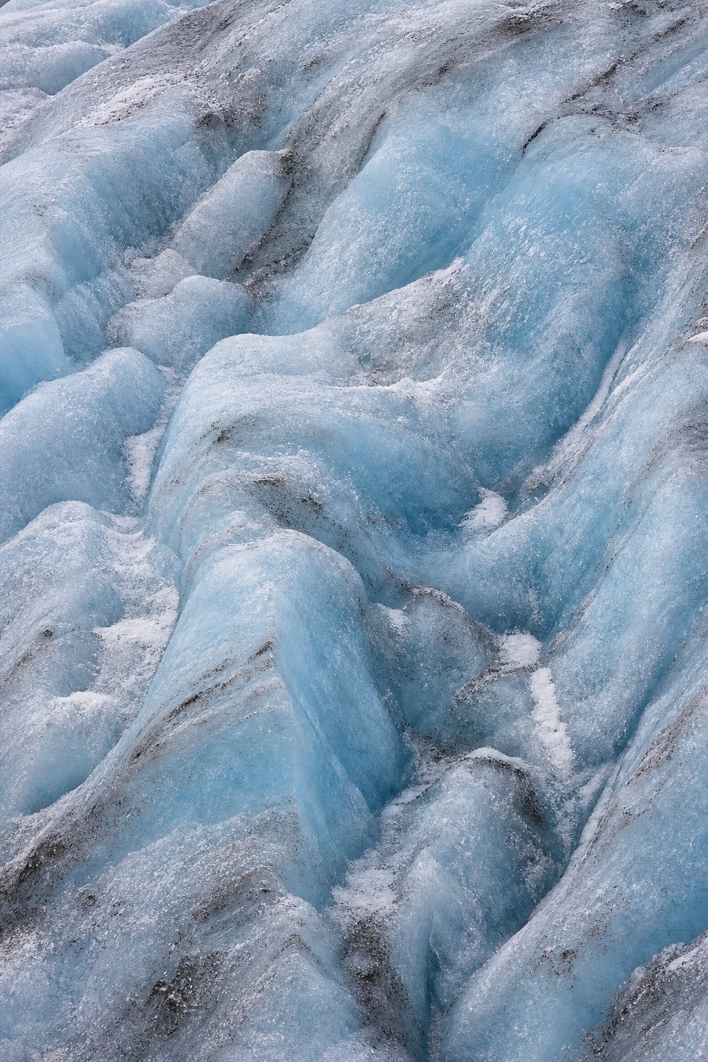 Close view of a compressed blue glacier wall with crevasse ridges and icy texture.