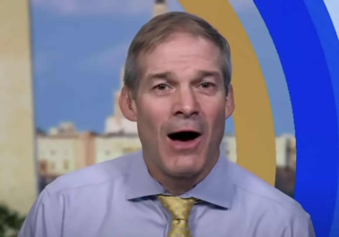 Man speaking in front of a blue and gold studio backdrop.