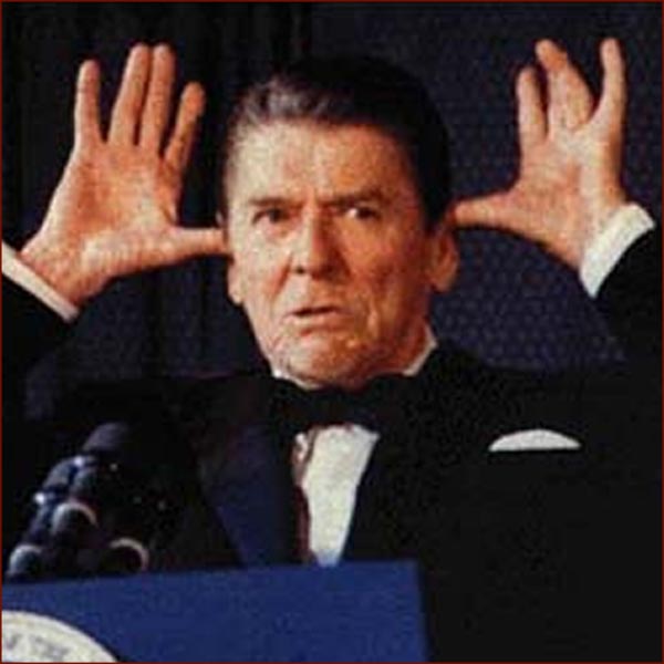 Ronald Reagan standing at a press conference with both hands raised