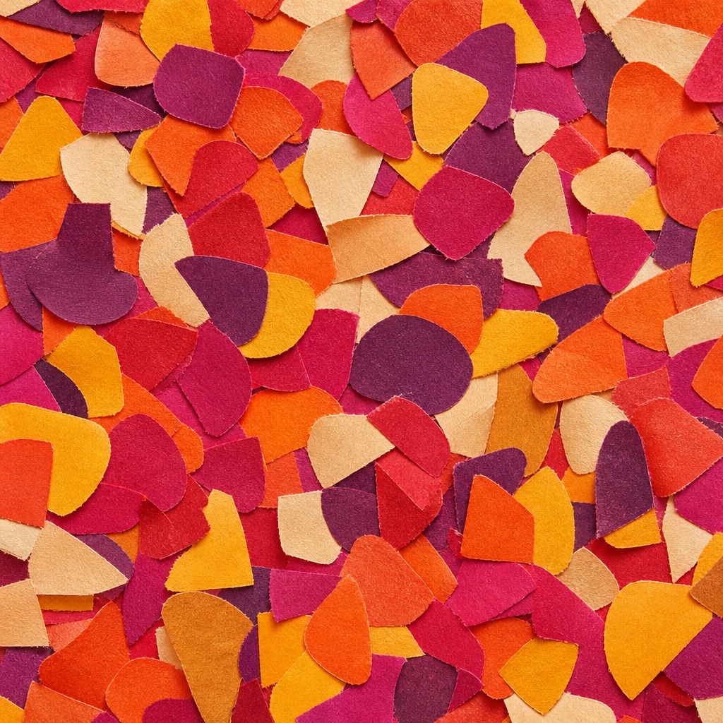 Colorful rounded paper confetti pieces in warm orange, red, and pink tones