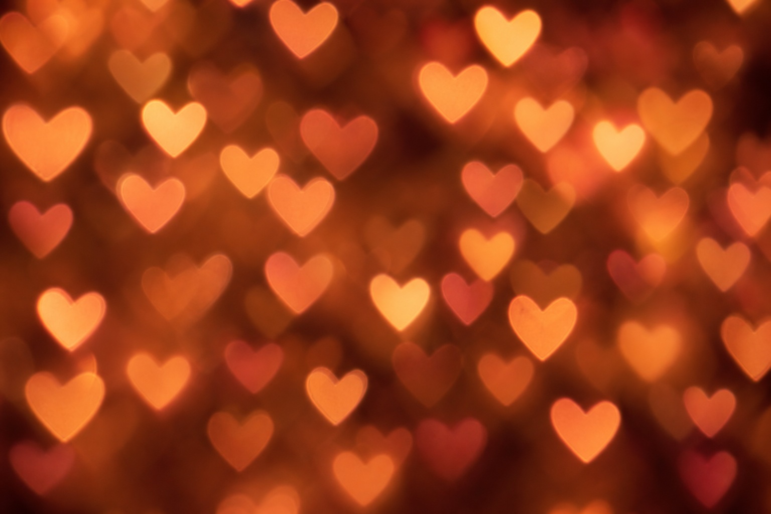 Soft pink heart-shaped bokeh lights glowing against a dark blurred background