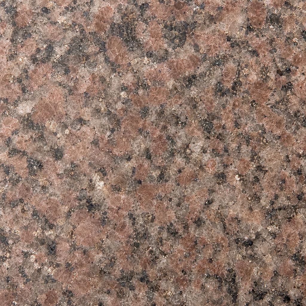 Rose granite surface with speckled mineral grain and subtle mica shimmer