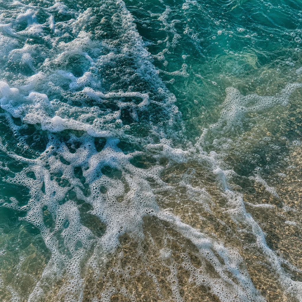 White sea foam and swirling currents over deep teal ocean water