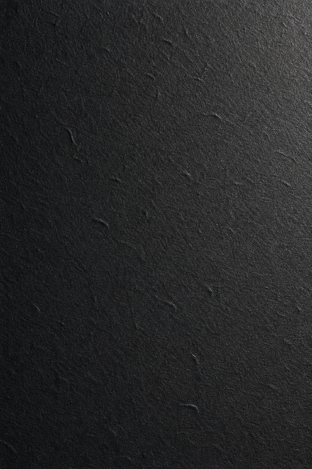 Dark charcoal paper surface with subtle embossed micro press texture.