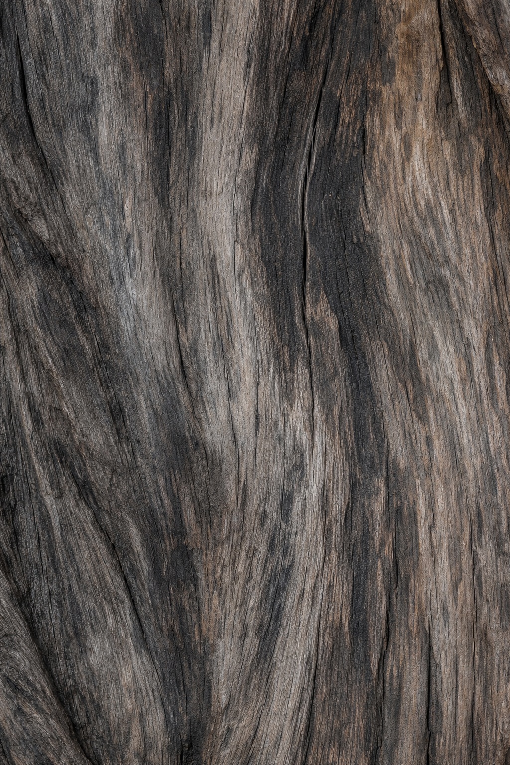 Close-up of weathered charcoal brown reclaimed wood with visible grain and worn texture.