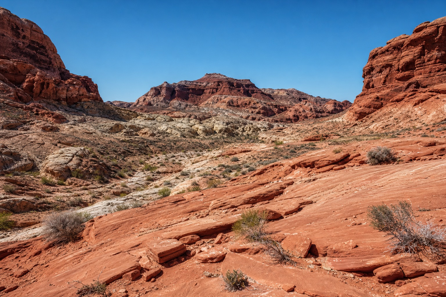 Red sandstone canyon basin with layered rock formations under a clear blue sky