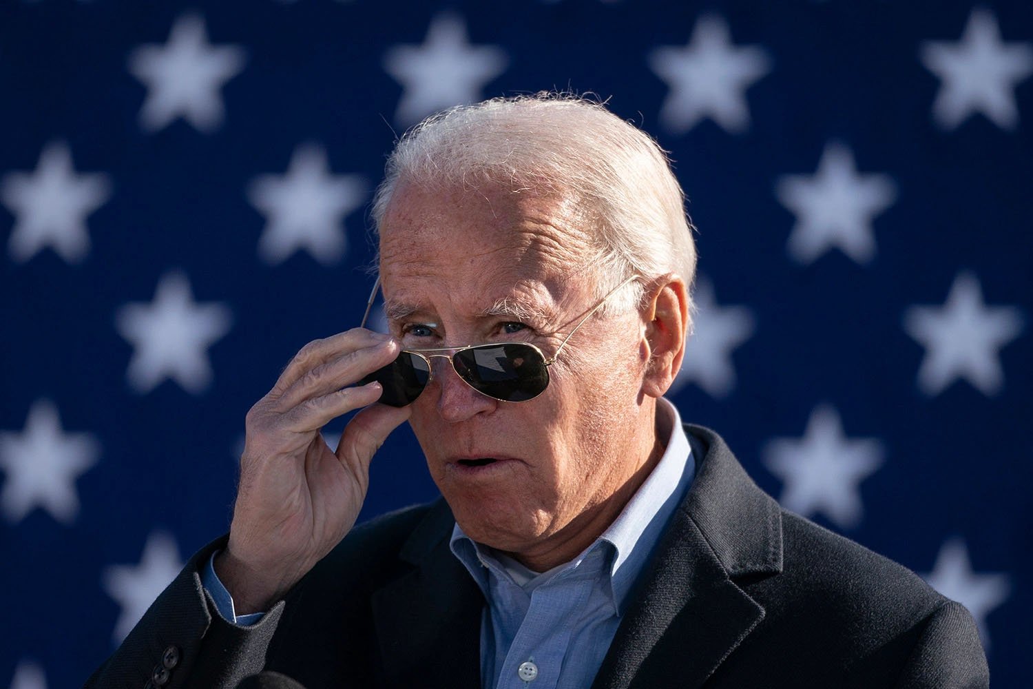 President Biden in sunglasses in front of a starry blue background.