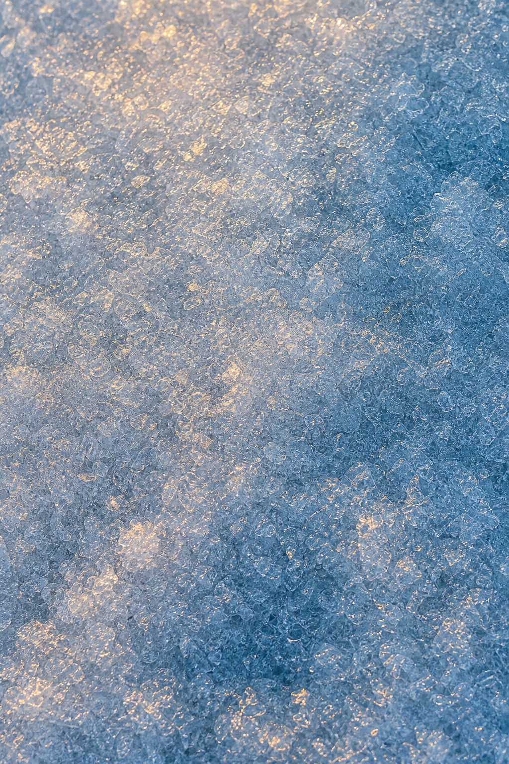 Blue frosted ice surface with warm light and fine rime granules