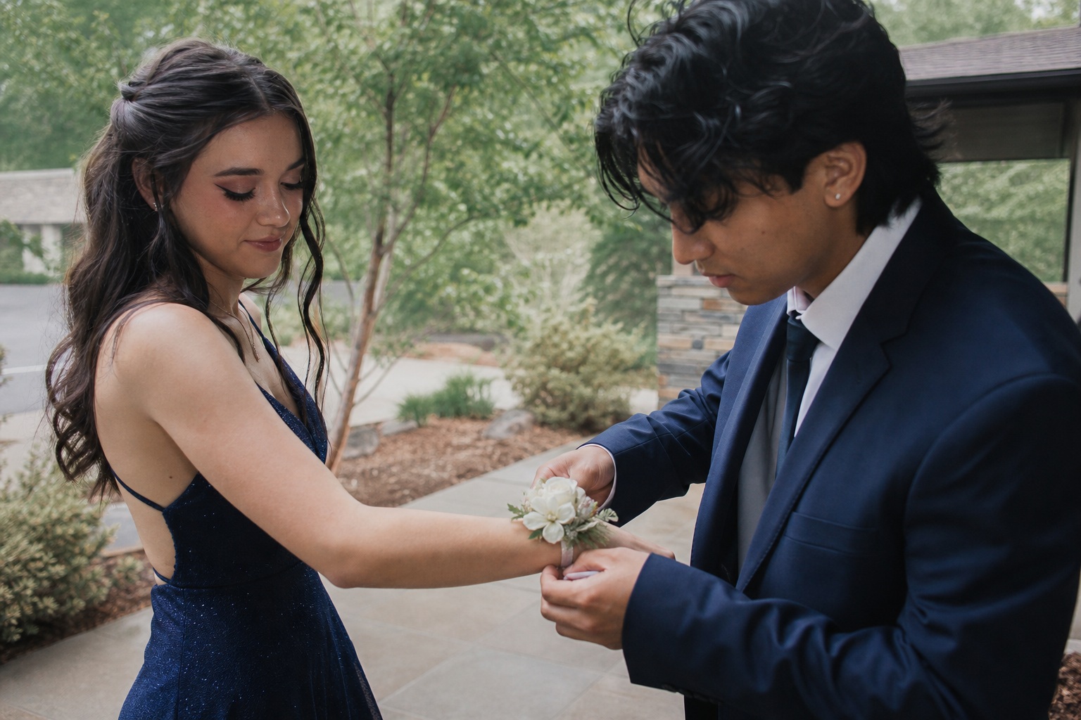 Young couple outdoors as he helps her with a wrist corsage