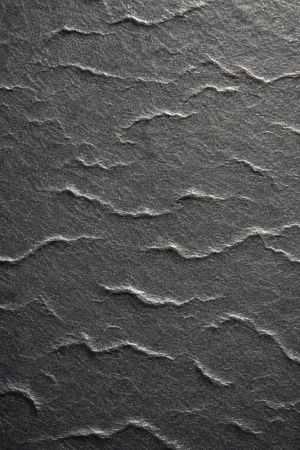 Dark charcoal embossed paper texture with broken wave ridges across the surface