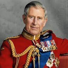 King Charles III wearing a red military uniform with medals and gold braided trim