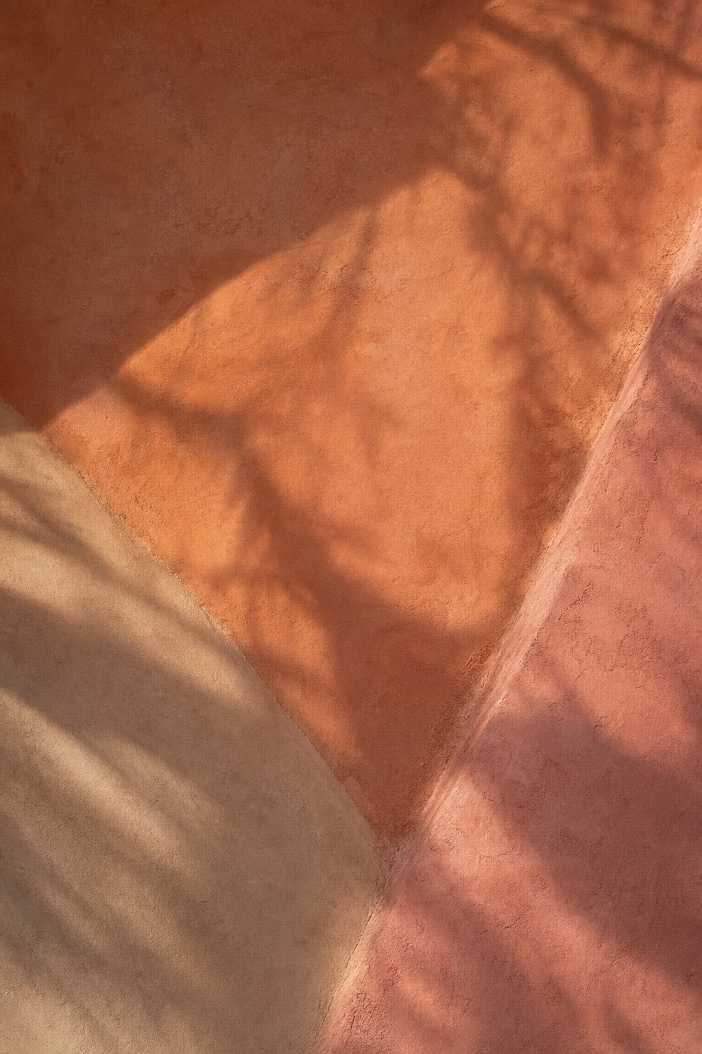 Warm plaster wall with diagonal shadows and soft evening light