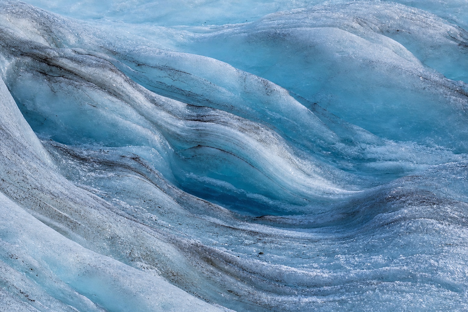 Blue glacial ice with shallow crevasse folds and textured crevice detail.