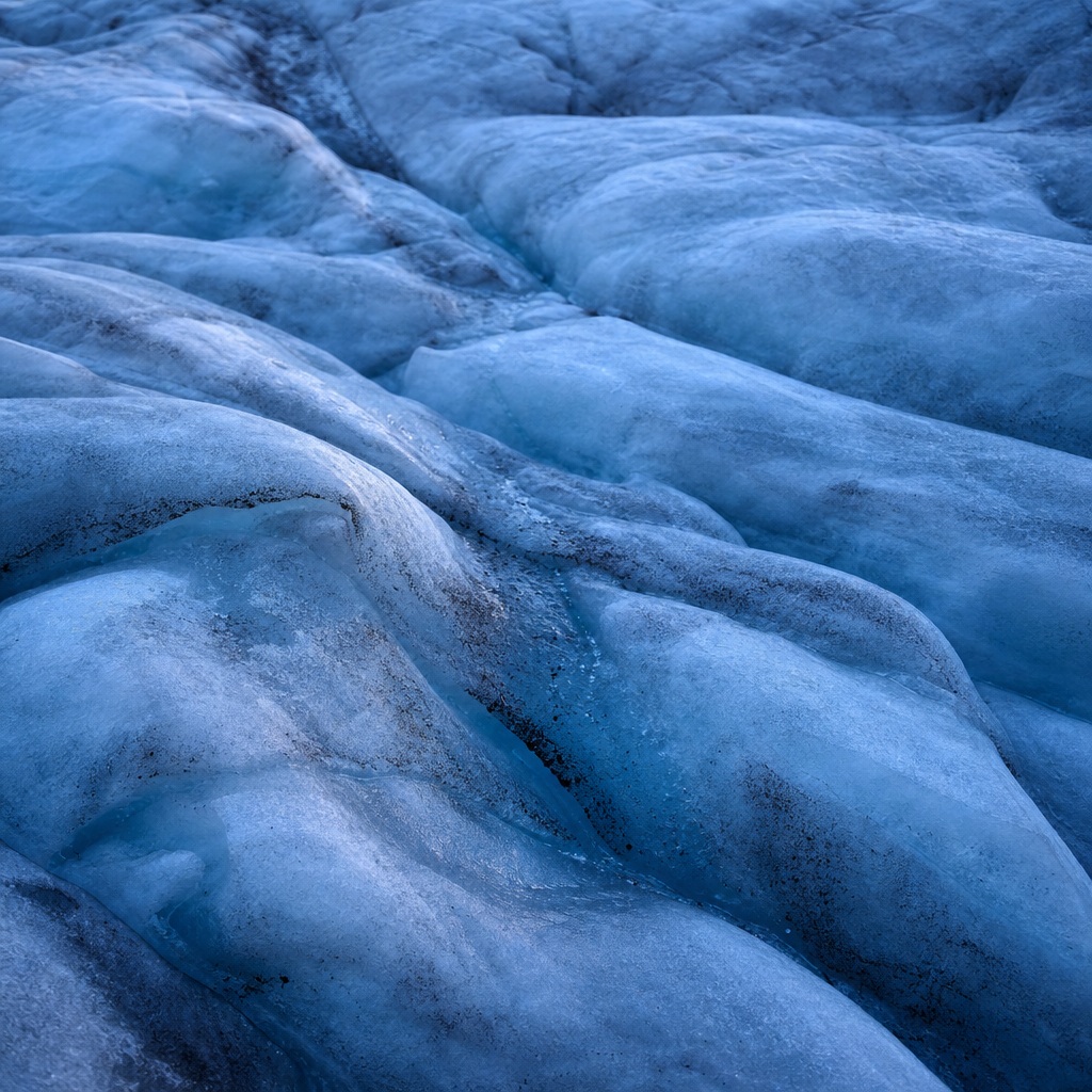 Blue glacial ice with shallow crevasse folds and textured ridges