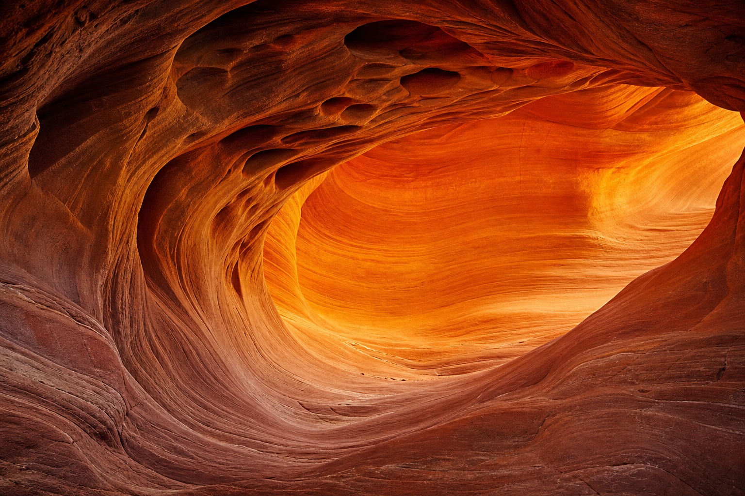 Curved sandstone alcove glowing with warm orange light and layered rock texture.