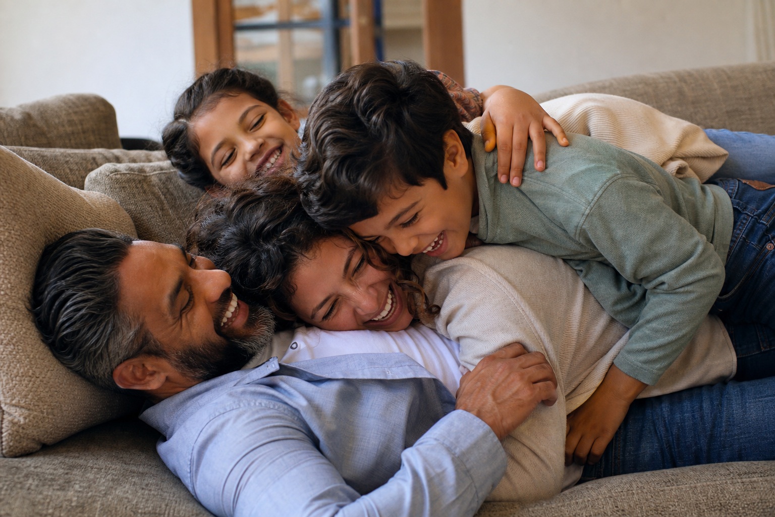 Four family members cuddling together on a sofa in a candid indoor scene