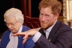 Prince Harry gesturing beside the Queen at an indoor event