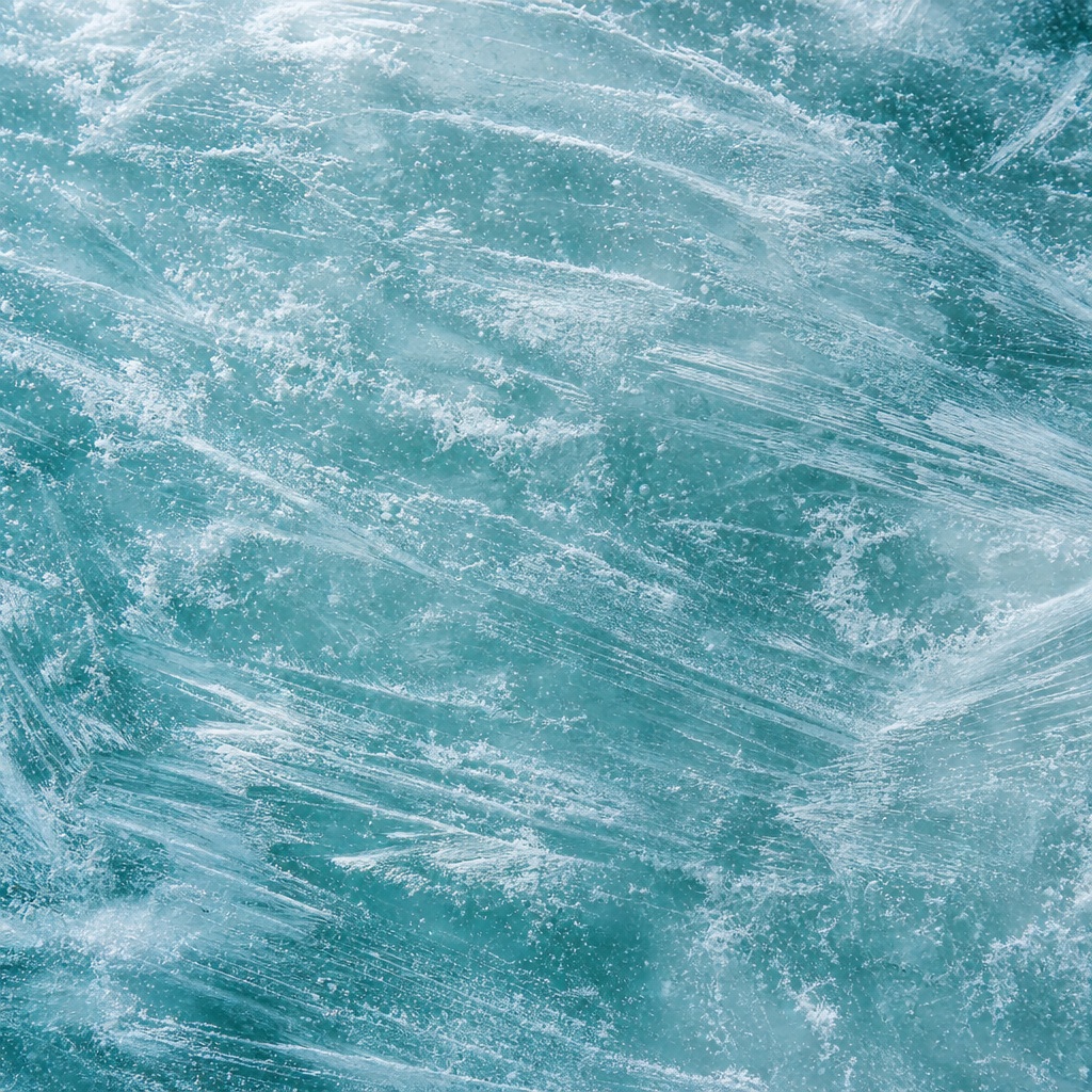 Aqua teal frosted ice surface with wind-etched streaks and fine white frost patterns