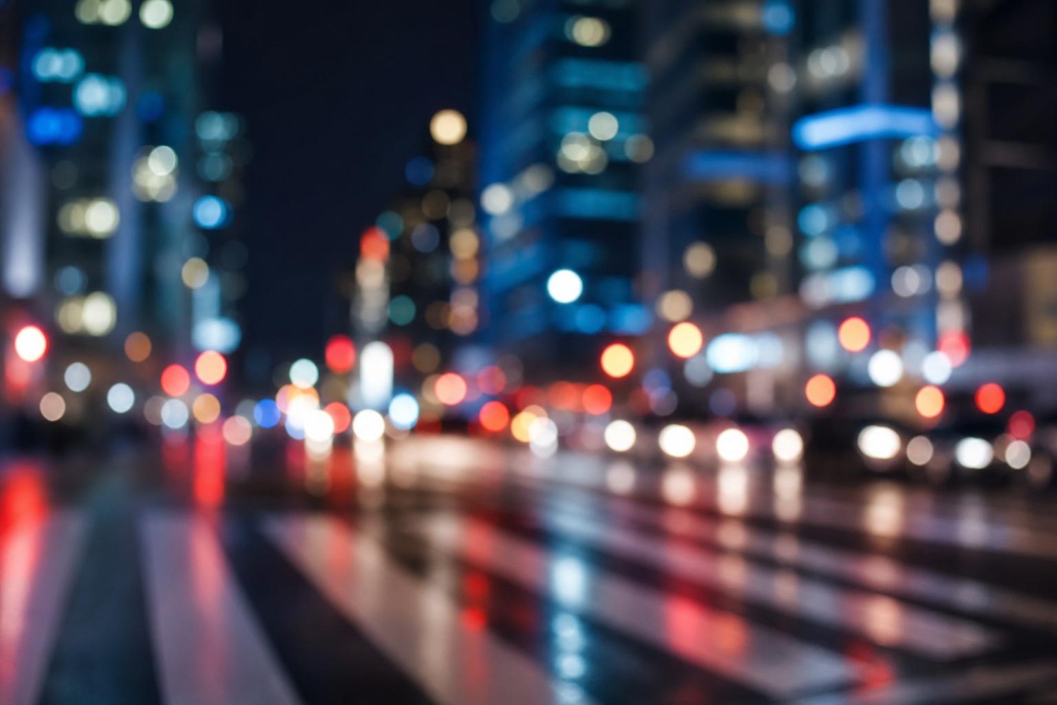 Blurred nighttime city lights reflected on a street with soft crosswalk bokeh