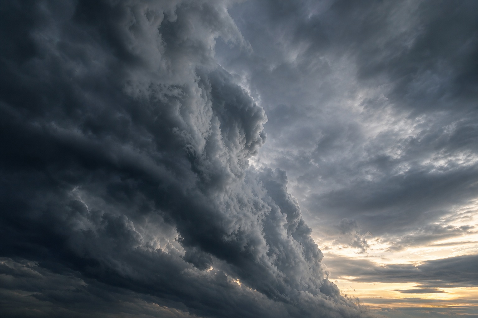 Dark storm clouds forming a dramatic wall across an overcast sky at sunset