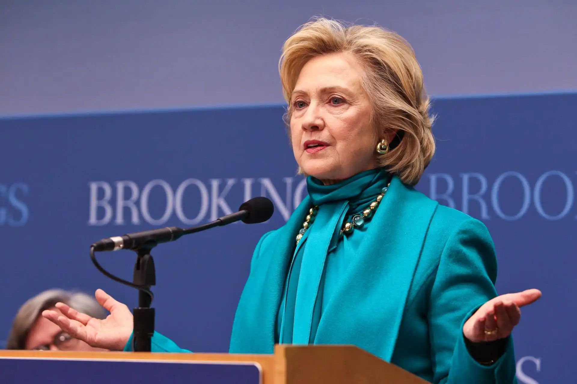 Hillary Clinton speaking at a podium in front of a Brookings backdrop