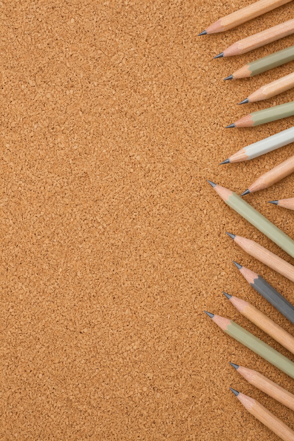 Vertical cork texture background with pencils lined along the right edge