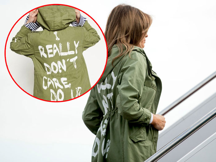 Woman in a green jacket standing on stairs with a protest message on the back.