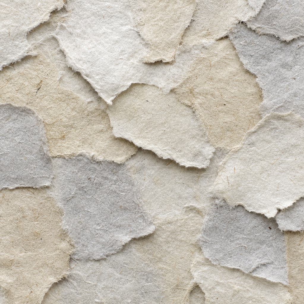 Torn layers of beige and gray fiber paper creating a handmade texture
