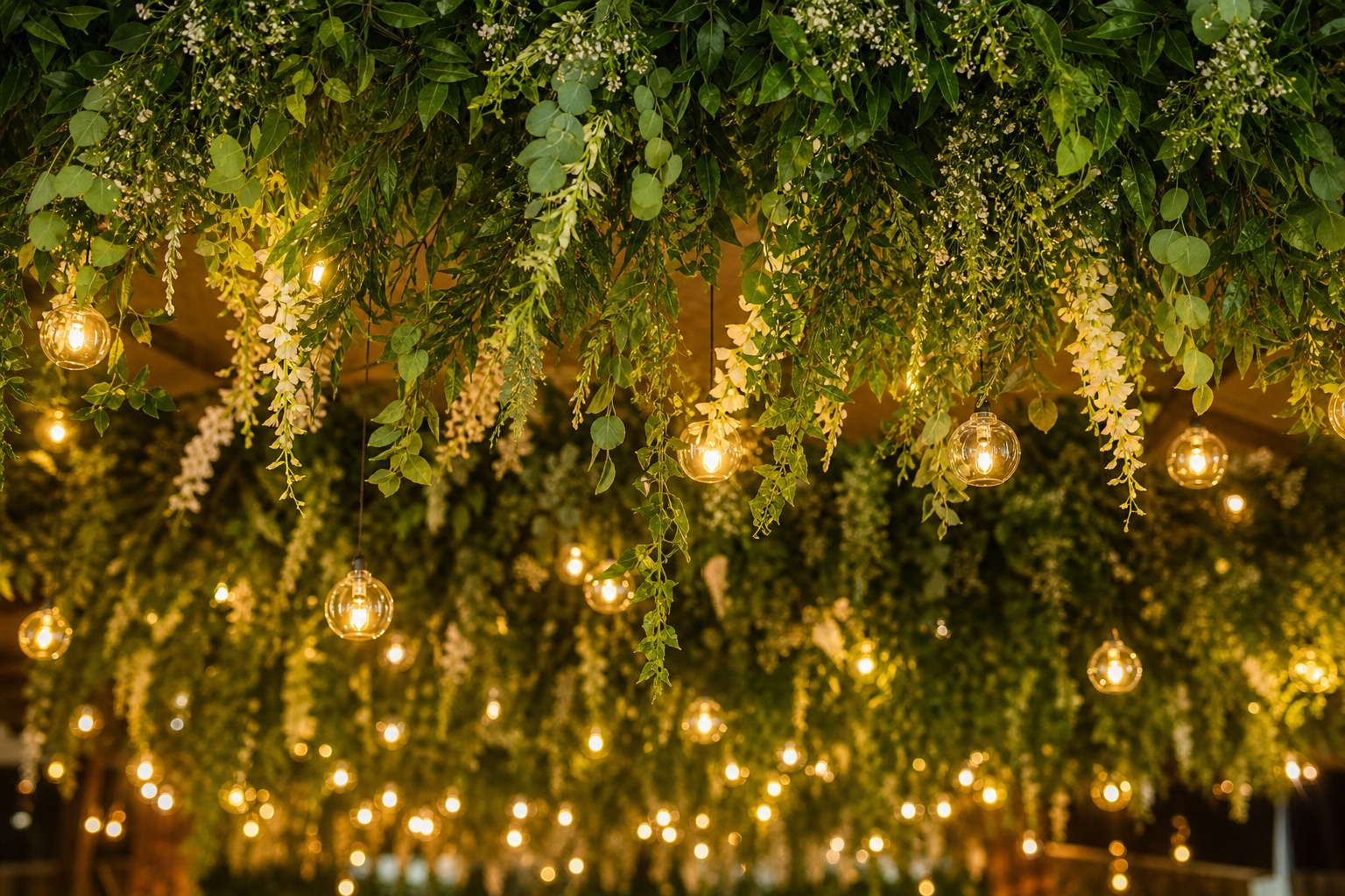 Hanging greenery with warm string lights and a romantic wedding-style backdrop