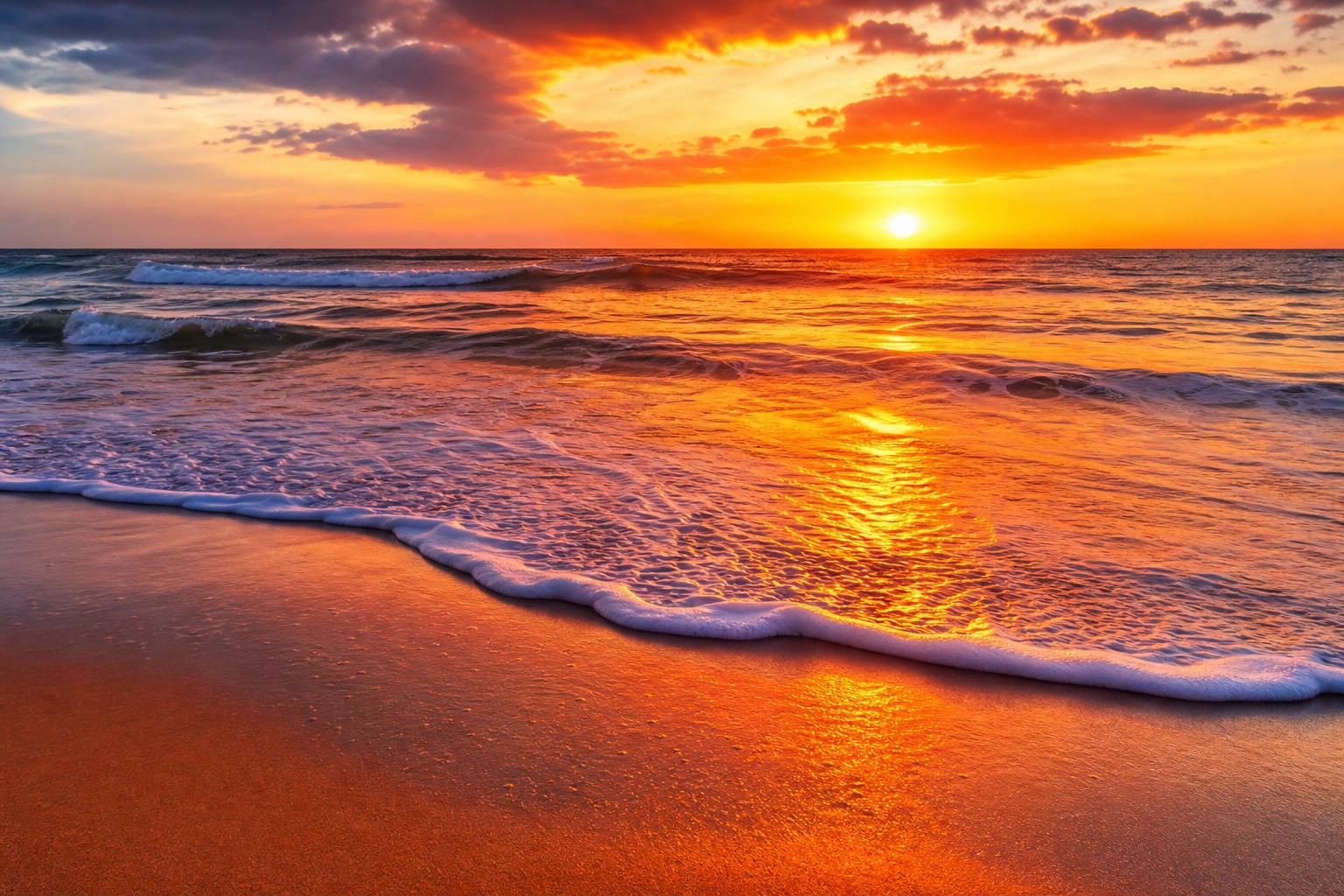 Sunset over ocean waves washing onto a sandy beach at golden hour