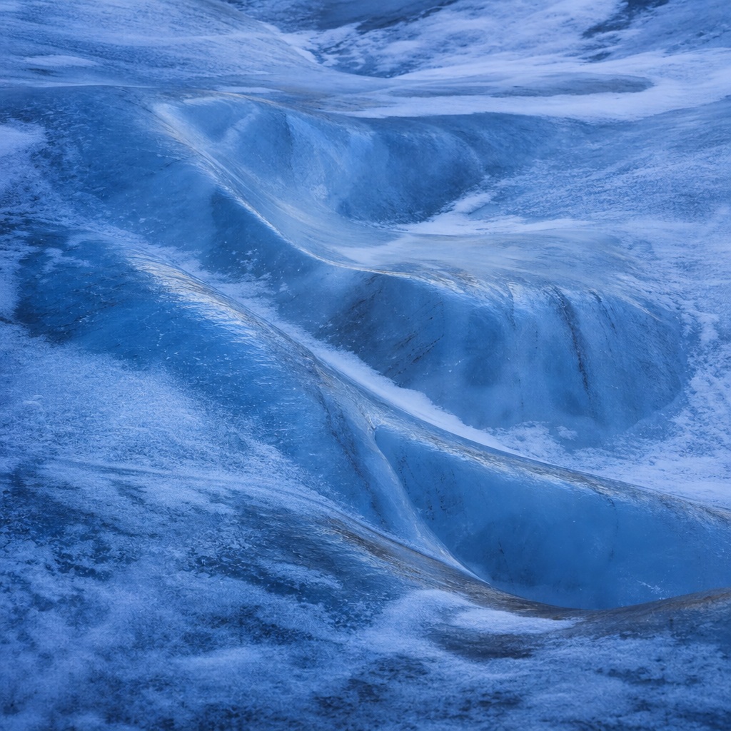 Blue glacier ice with deep crevasses and smooth polished channels