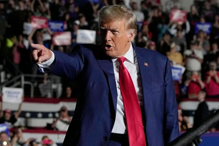 Donald Trump points while speaking at a campaign rally in front of a crowd.