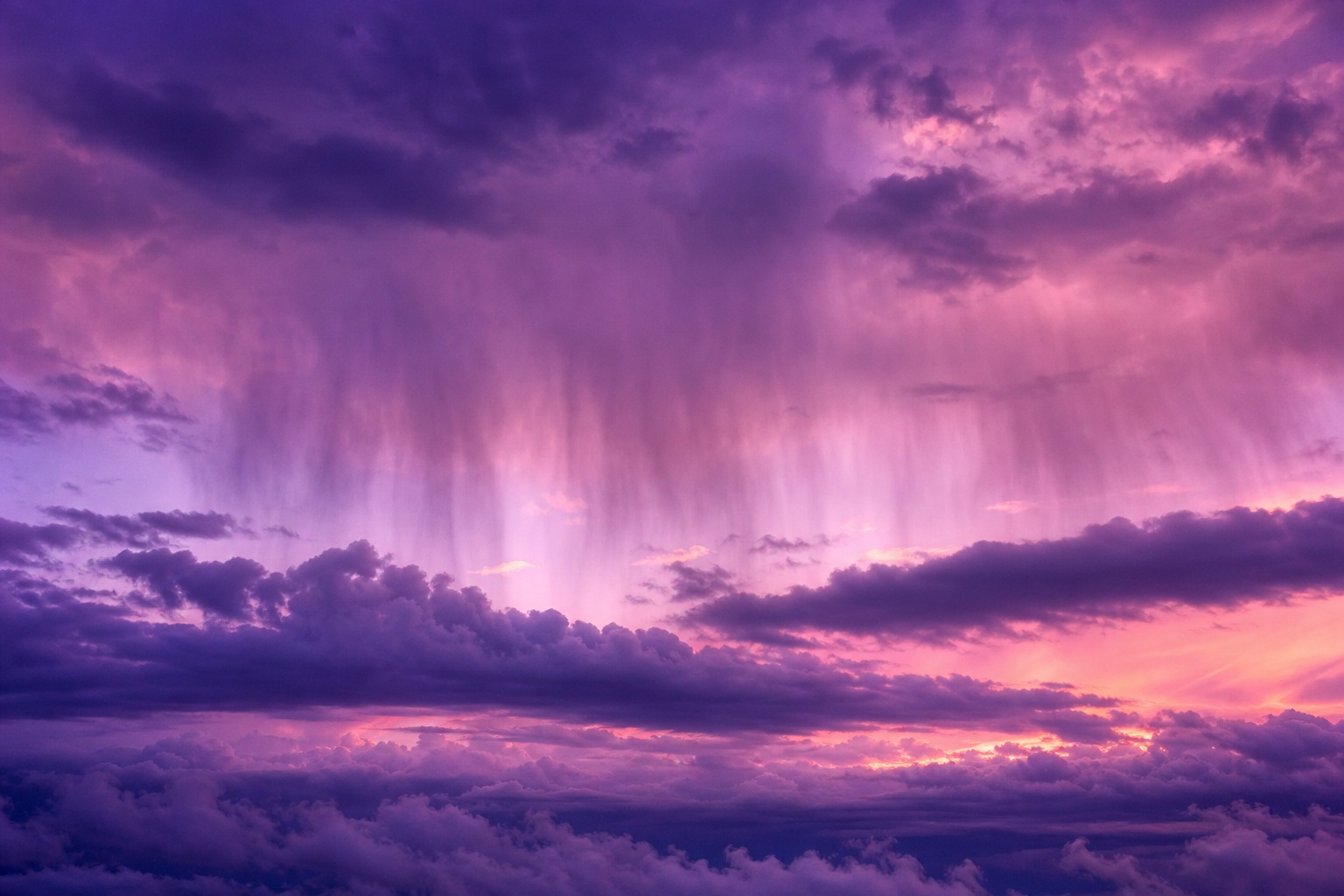 Lavender and pink cloudscape with a dramatic rain curtain falling from glowing clouds