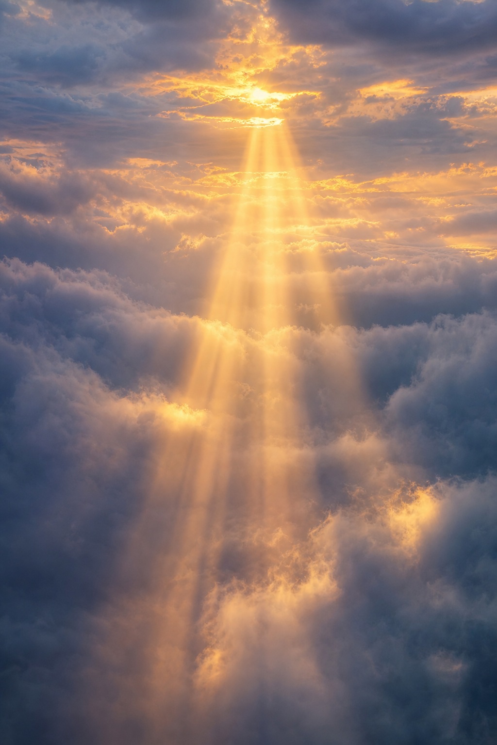 Golden sunbeams shining through layered clouds and soft fog in a dramatic sky