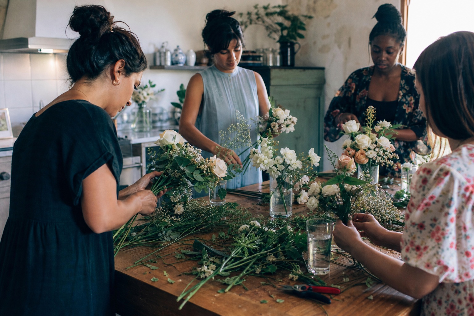 People arranging flowers and wedding details around a wooden table in a candid prep scene