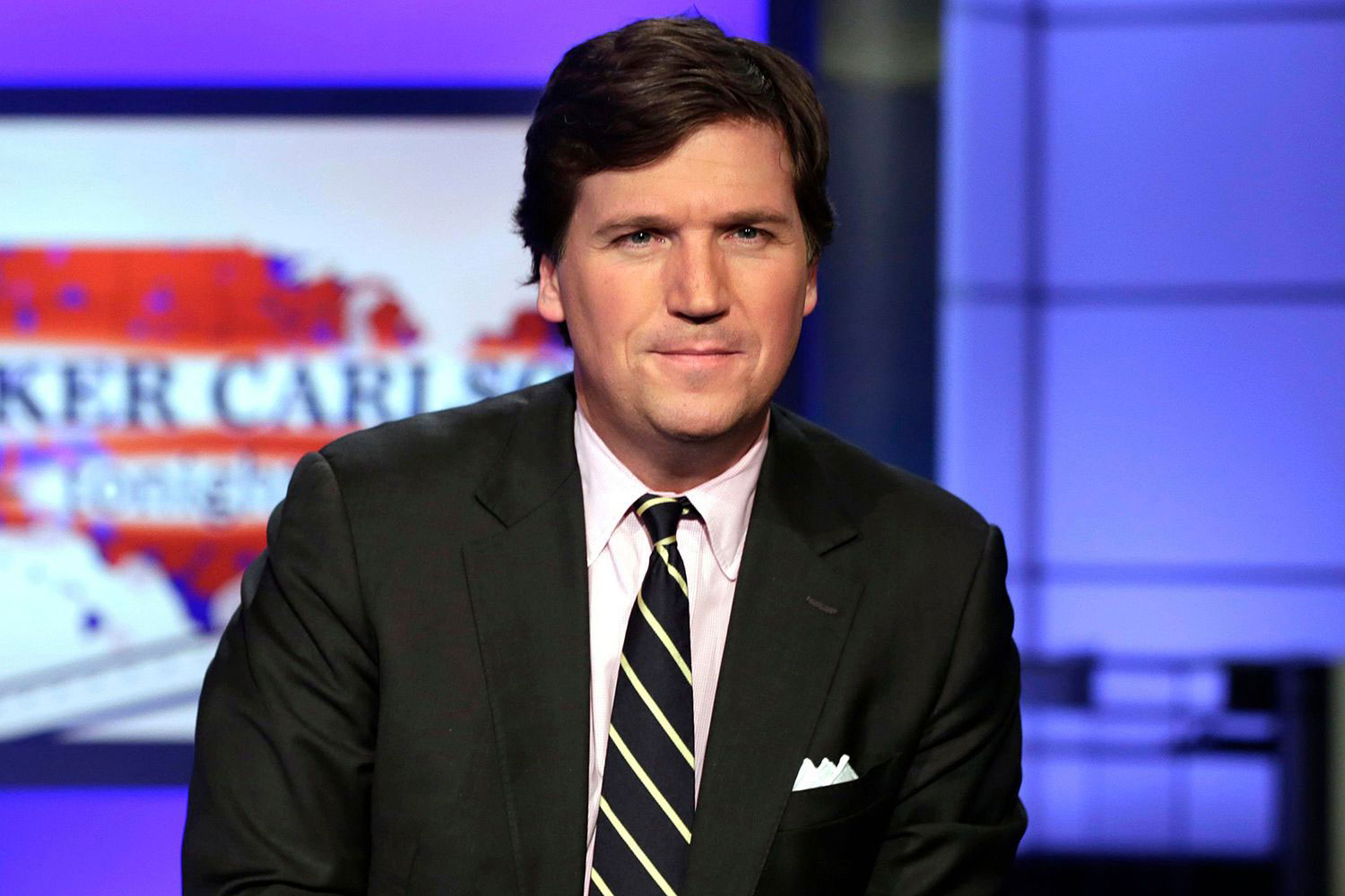 Tucker Carlson speaking on a television screen with a studio backdrop